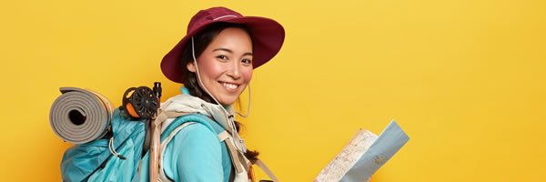 active korean female tourist carries big rucksack wears hat casual clothes holds map studies route has much things needed during traveling